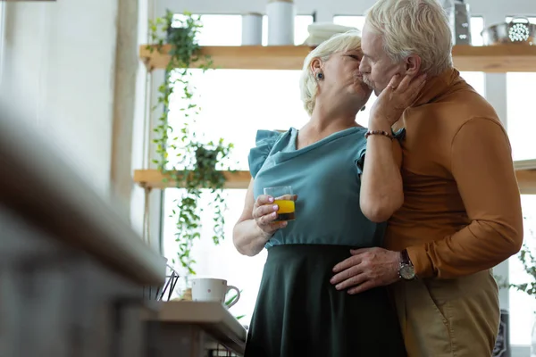 Beaming marido e mulher abraçando e beijando na cozinha . — Fotografia de Stock