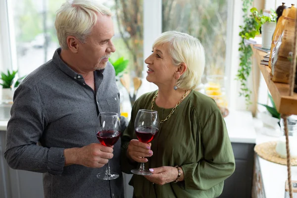 Щасливі літні подружжя обіймають і тримають окуляри з червоним вином . — стокове фото