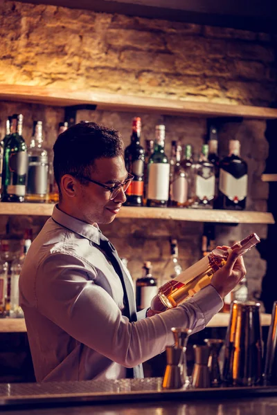 Dark-haired owner of bar holding bottle of whisky — Stock Photo, Image