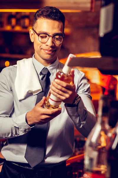Bohatý muž, který stojí v baru a drží láhev alkoholu — Stock fotografie