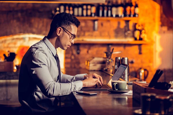 Businessman working remotely sitting at the bar stand