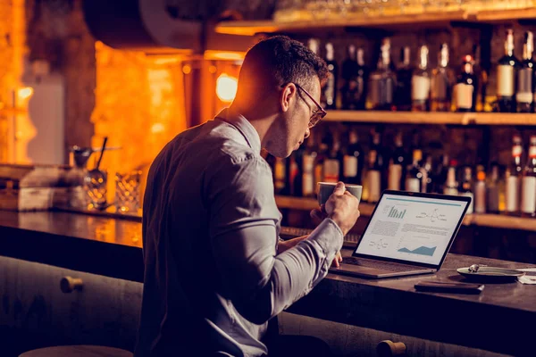 Dizüstü bilgisayar da çalışan ve kahve içen bir bar sahibi işadamı