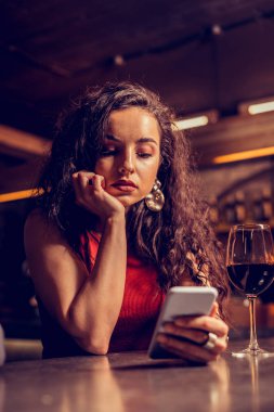 Tek başına şarap içen bir kadın barda erkek arkadaşını bekliyor.