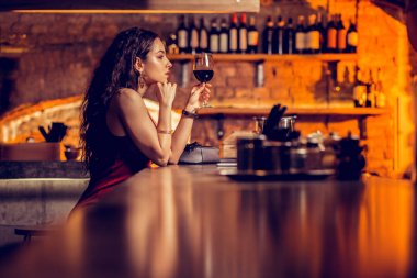 Barda tek başına şarap içen uzun saçlı güzel kadın