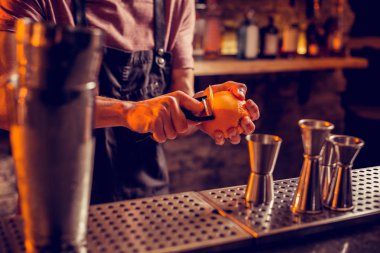 Siyah önlük barmen kokteyl için portakal kabuğu alarak