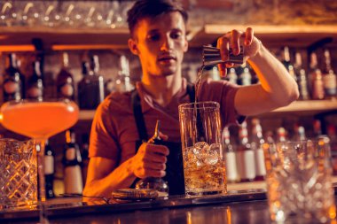 Koyu saçlı barmen buz ile cam içine alkol döker
