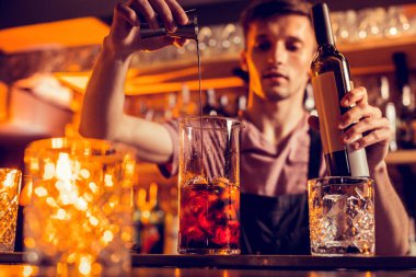 Yakışıklı genç barmen kokteyl içine alkol döküyor