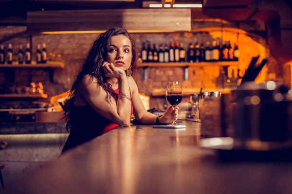 Long-haired woman drinking wine and waiting for her man — Stock Photo, Image