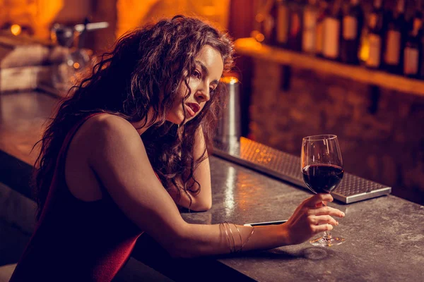 Curly woman feeling lonely drinking alone in bar