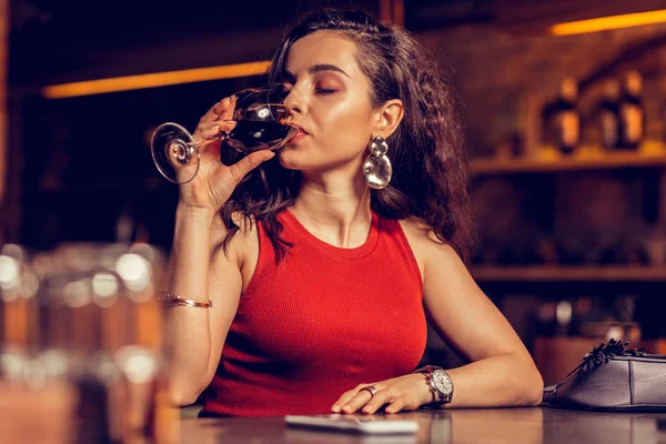 Mooie vrouw draagt mooie oorbellen rode wijn drinken — Stockfoto