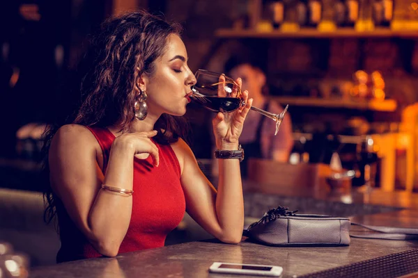 Woman wearing watch holding glass of wine and drinking — Stock Photo, Image