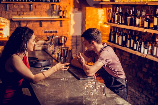 Mulher de cabelos escuros falando com barman e beber vinho — Fotografia de Stock