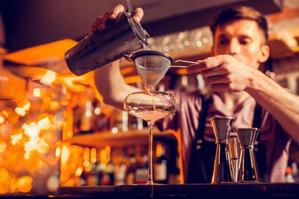 Dark-haired bartender using sieve while making cocktail — Stock Photo, Image