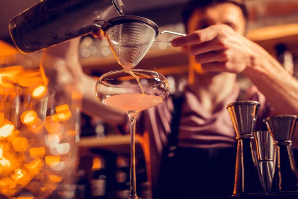 Barman derramando suco em vidro ao usar a peneira — Fotografia de Stock