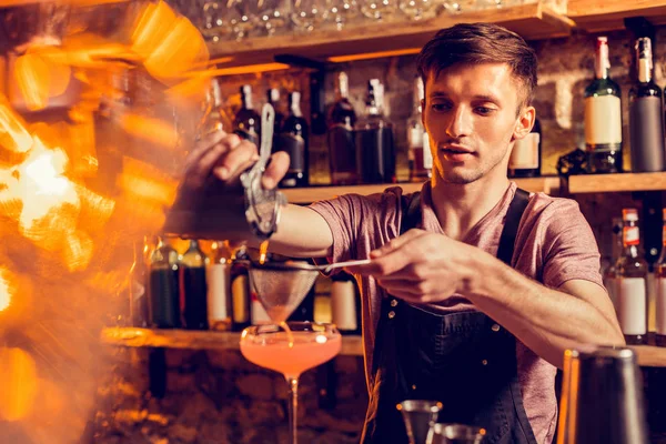 Barmann gießt Saft durch Sieb, während er Cocktail zubereitet — Stockfoto