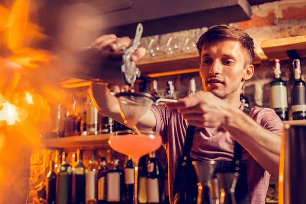 Barman si sente occupato mentre versa succo attraverso setaccio nel vetro — Foto Stock