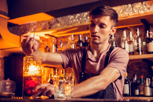 Bartender wearing black apron finishing making cocktail