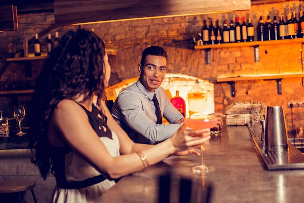 Krullend vrouw drinken cocktail in Bar praten met de mens — Stockfoto