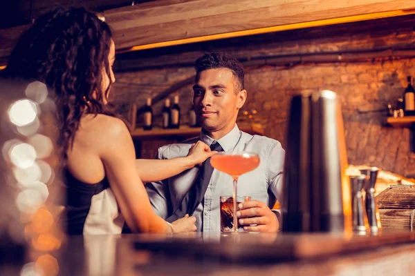 Boyfriend making funny face while caring girlfriend fixing his tie