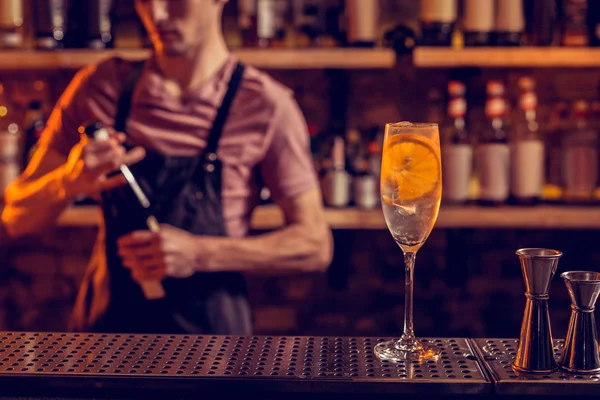 Бармен, стоящий у стойки бара со стаканом алкоголя и лимоном — стоковое фото