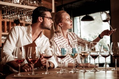 Genç şarap garsonu kırmızı sıvıyı kontrol ediyor.