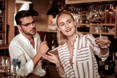 Şarap kadehine bakan pozitif memnun sarışın barmen