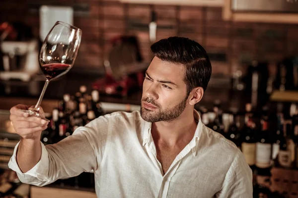 Jovem morena homem olhando para o copo de vinho — Fotografia de Stock