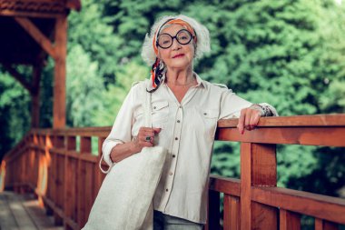 Çekici yaşlı kadın açık havada ahşap köprü üzerinde poz