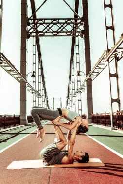 Yogi dışarıda akroyoga yaparken ortağını destekliyor.