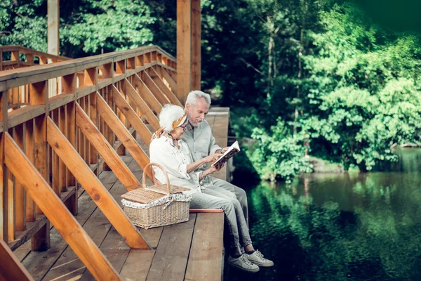 Zubící se manželé, kteří sedí a čtou knihu dohromady. — Stock fotografie