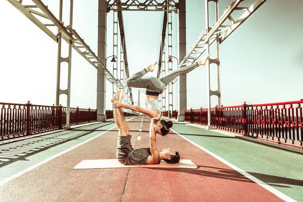 Jovem yogi em um tapete segurando seu parceiro — Fotografia de Stock