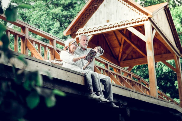 Couple joyeux dans les années portant des vêtements blancs profiter d'un livre Photo De Stock