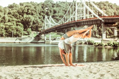 Genç sportif çift güneş doğarken esneme egzersizi yapıyor.