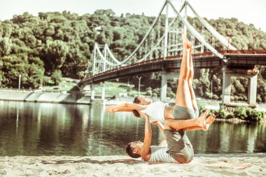 Yogi egzersiz minderinde partnerini dengeliyor.