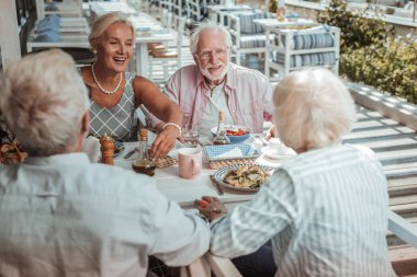 Olumlu memnun olgun insanlar akşam yemeği sırasında konuşurken