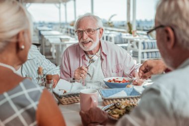 Neşeli gri saçlı adam arkadaşlarını dinliyor