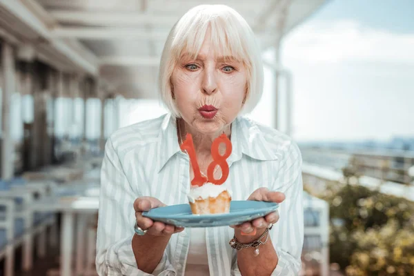 Концентрированная пожилая женщина загадывает желание на день рождения — стоковое фото