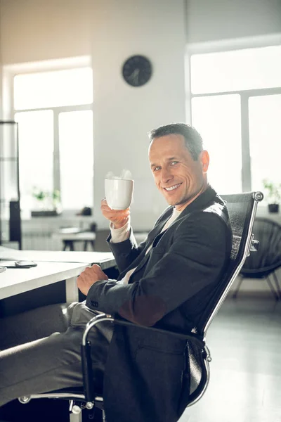 Businessman feeling satisfied after work while drinking coffee