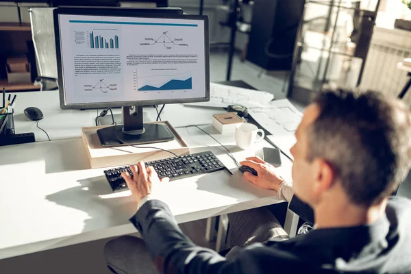 Geschäftsmann sitzt mit seinem Computer am Tisch im Büro — Stockfoto