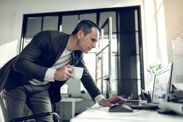 Empresario sosteniendo taza de café leyendo e-mail en el ordenador portátil — Foto de Stock