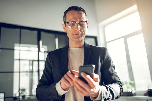 Hombre de negocios próspero con gafas escribiendo mensaje en el teléfono —  Fotos de Stock