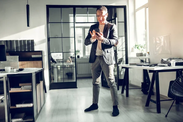 Uomo d'affari in piedi in ufficio e utilizzando il suo smartphone — Foto Stock