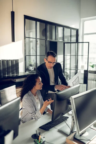 Lockige Assistentin im Gespräch mit ihrem Chef, der einige Fragen hat — Stockfoto