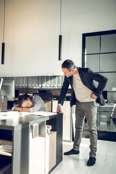 Furioso capo guardando la sua segretaria dormire sul tavolo — Foto Stock
