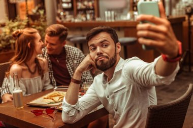 Arkadaşları arka planda sarılırken üzgün adam selfie'leri.
