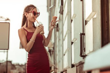 Sokaklarda yürürken buz-latte içen koyu saçlı hoş büyüleyici bayan