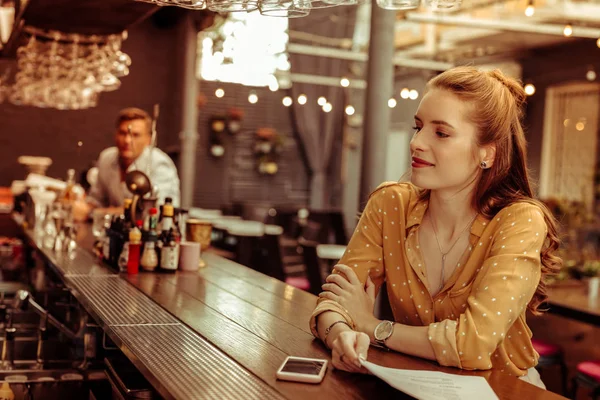 Senhora encantadora com cabelo ruivo sentado no balcão do bar — Fotografia de Stock