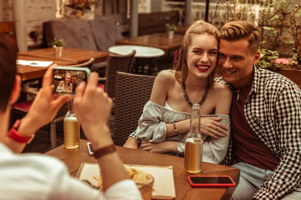 Gelukkig paar wordt gefotografeerd door hun vriend aan de bar. — Stockfoto