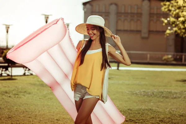 Charming arresting young lady posing with a pink swimming mattress