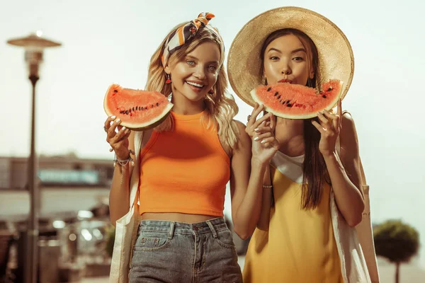 Face-portrait of women holding watermelon pieces in hands